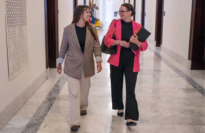 Two people discussing animal welfare policy while walking down a hall