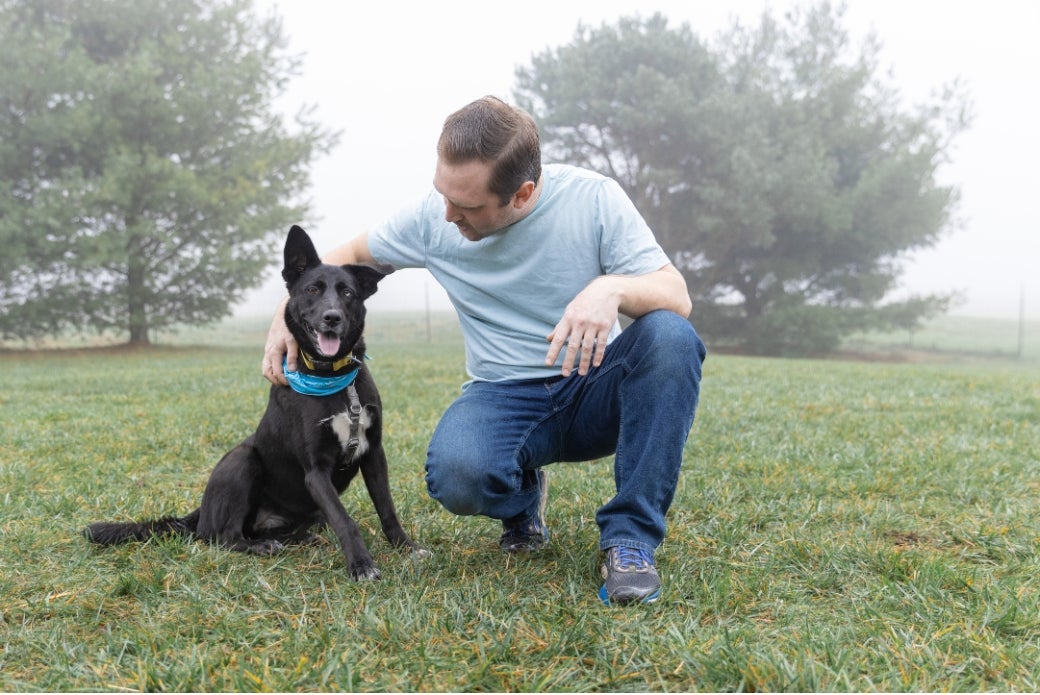 adopter petting his dog outside