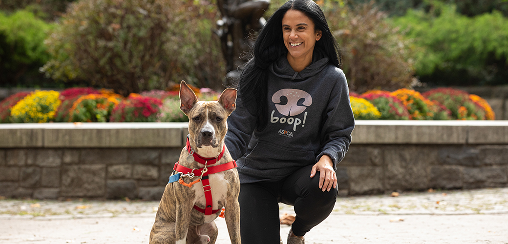 a woman and dog outside with an aspca hoodie