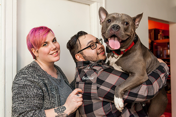 Young couple holding pit bull and posing for camera
