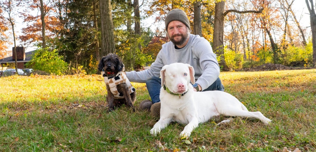 Man sitting in grass with two dogs