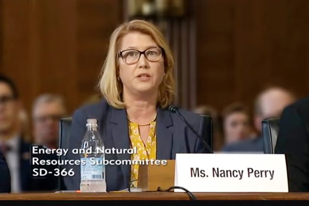 Woman sitting at desk with name placard reading Ms. Nancy Perry