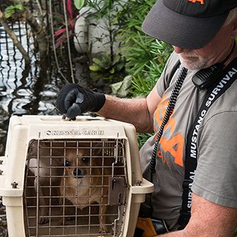 ASPCA volunteer holding a dog in a carrier