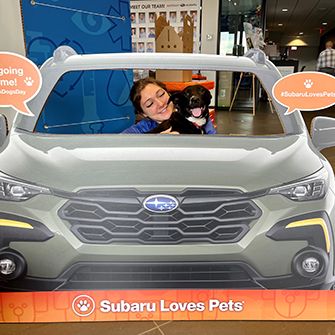 A woman with a black dog in a Subaru Share the Love event cut out