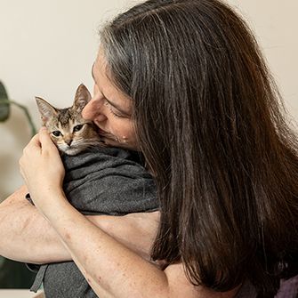 a woman hugging a cat wrapped in a blanket