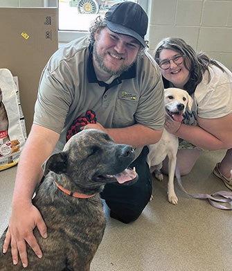 Two Terrebonne Parish Animal Services team members petting two dogs